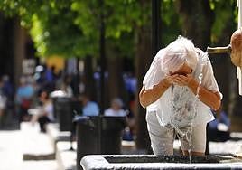 Una mujer se refresca y bebe agua para hacer frente al calor. EFE