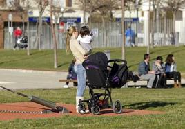 Una mujer pasea por un parque con una niña de corta edad.