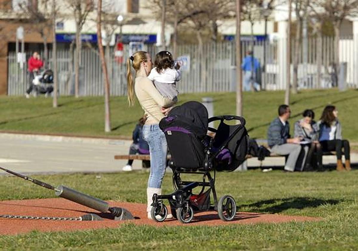 Una mujer pasea por un parque con una niña de corta edad.