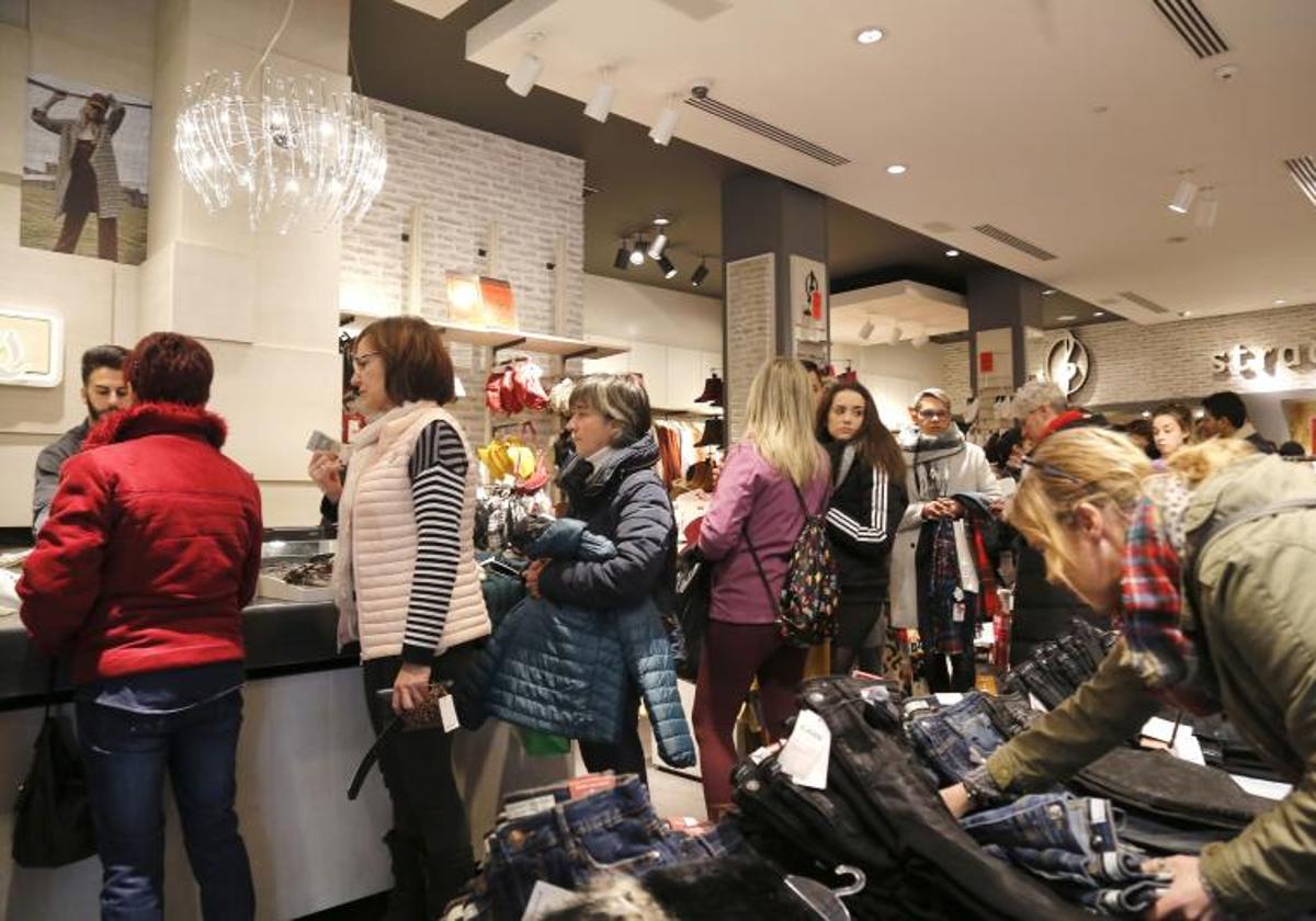 Clientes guardan cola para pagar en una tienda.