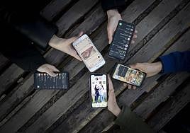 Varios jóvenes muestran las redes sociales en sus teléfonos móviles.