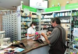 Un cliente compra en una farmacia de Palencia.