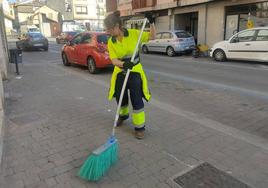 Una trabajadora del servicio municipal barre una calle de la localidad cuellarana.