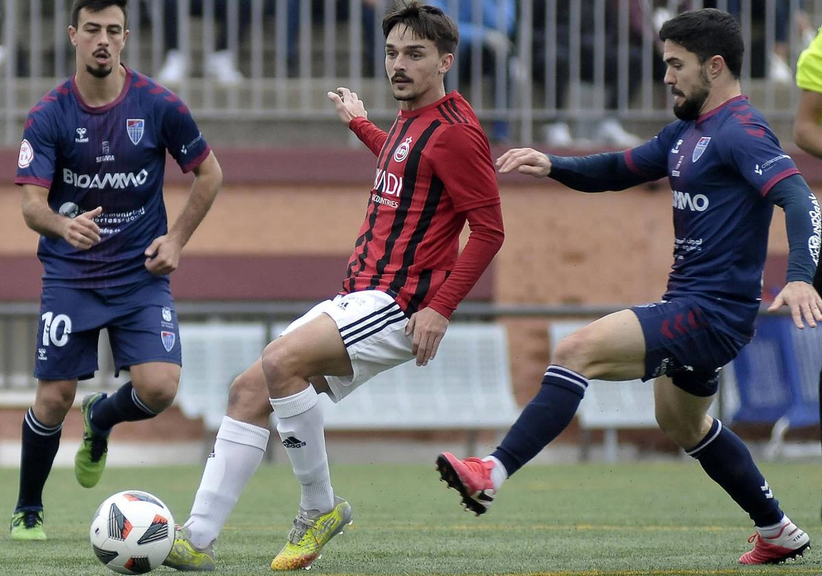 Un jugador del Adarve rodeado por dos azulgrana en el partido de ida de esta temporada.