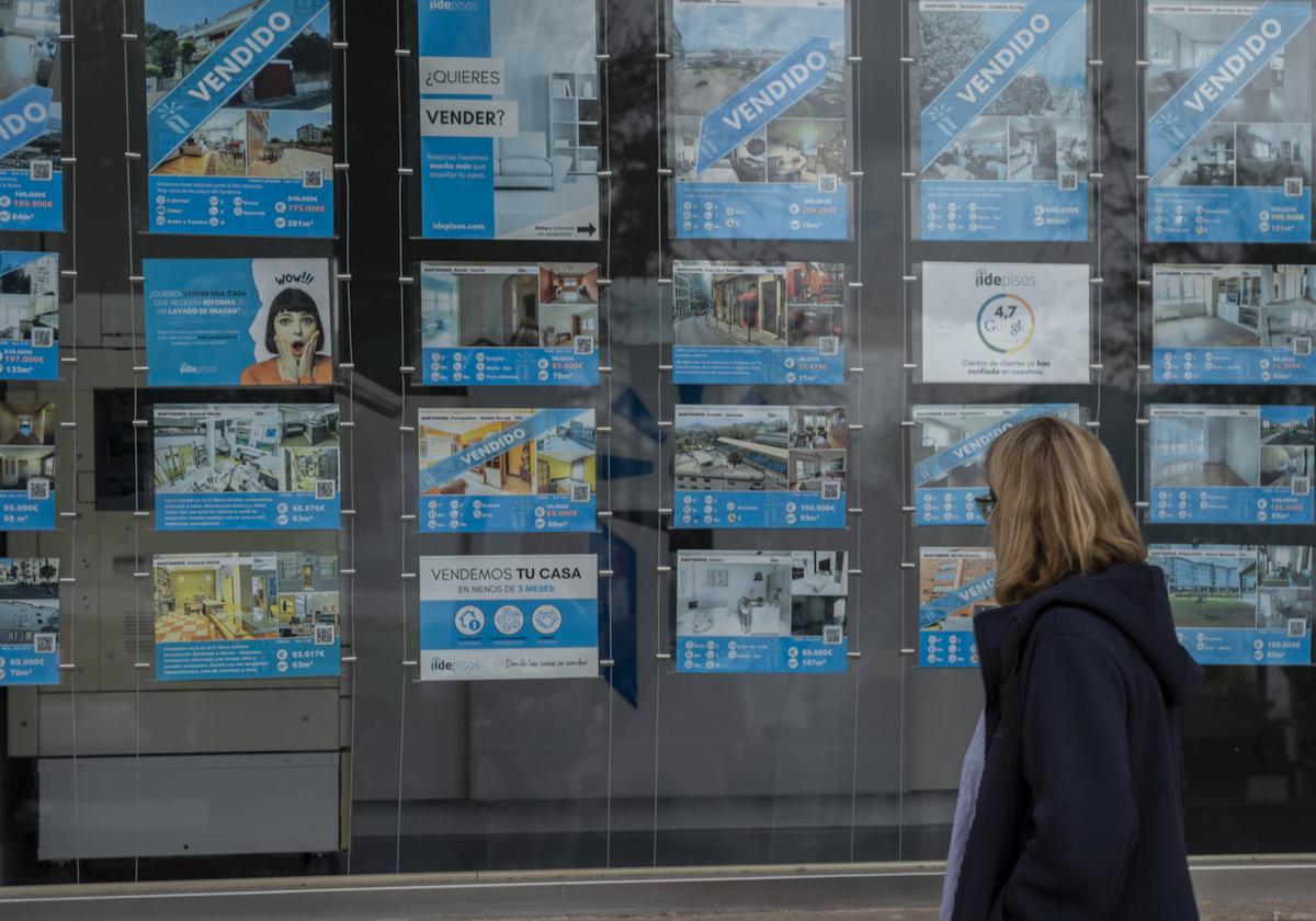 Una mujer pasa ante el escaparate de un inmobiliaria.