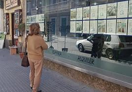 Una mujer mira el escaparate de una inmobiliaria en una imagen de archivo