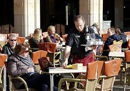 Un camarero sirve consumiciones en una terraza de la Plaza Mayor de Salamanca.
