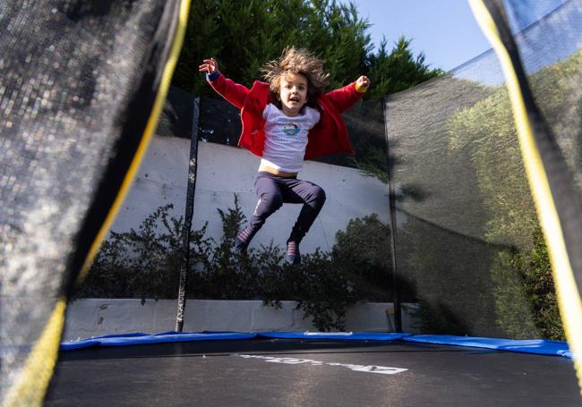 Valeria salta en una cama elástica en el jardín de su casa.