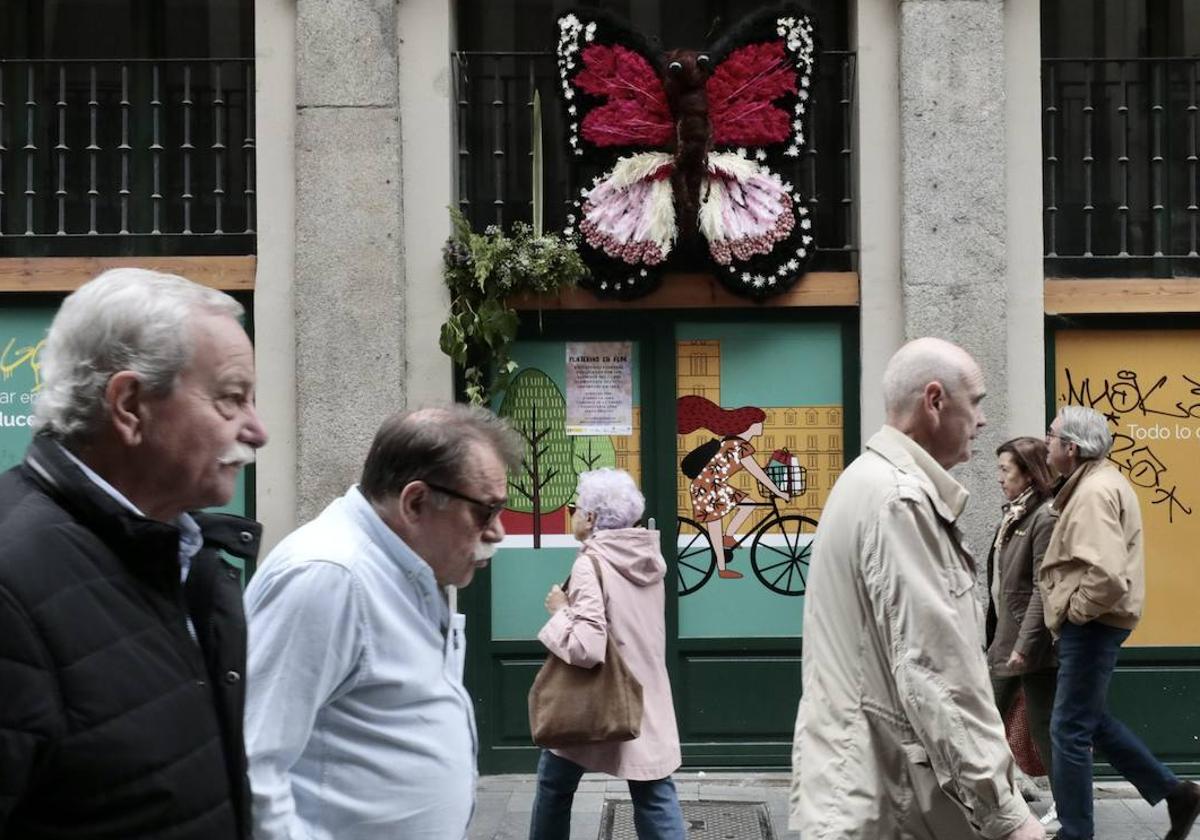 Varias personas caminan delante de una de las mariposas que decoran la calle Platerías.