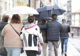 Los viandantes se protegen de la lluvia en Angustias durante la breve tormenta del pasado jueves.