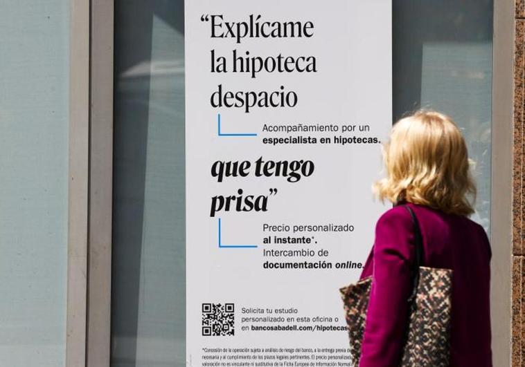 Una mujer ante un cartel bancario sobre las hipotecas.