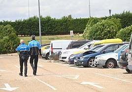 Los dos agentes de la Policía Local destinados en el depósito pasean por delante de los vehículos intervenidos por orden judicial.