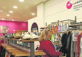 Una mujer mira ropa en la tienda de Cáritas.