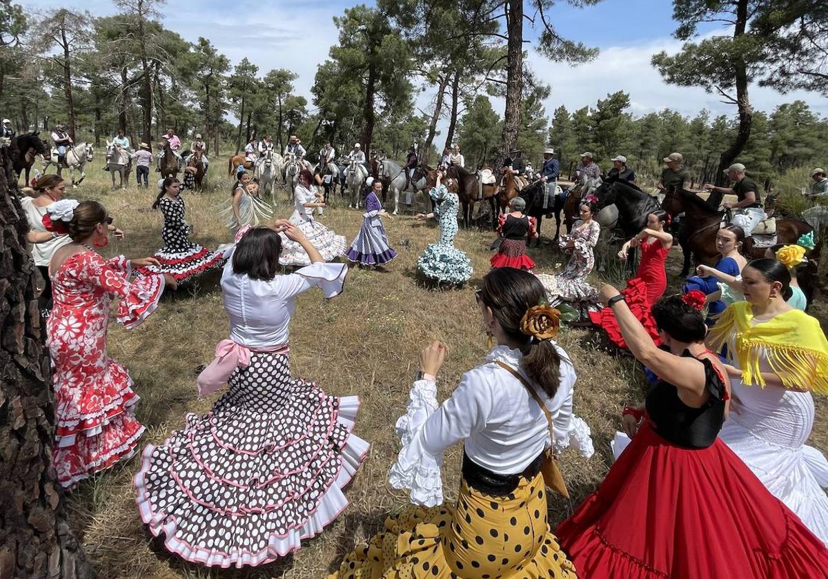 Mujeres vestidas con trajes de flamenca y caballistas, en un momento de la feria.