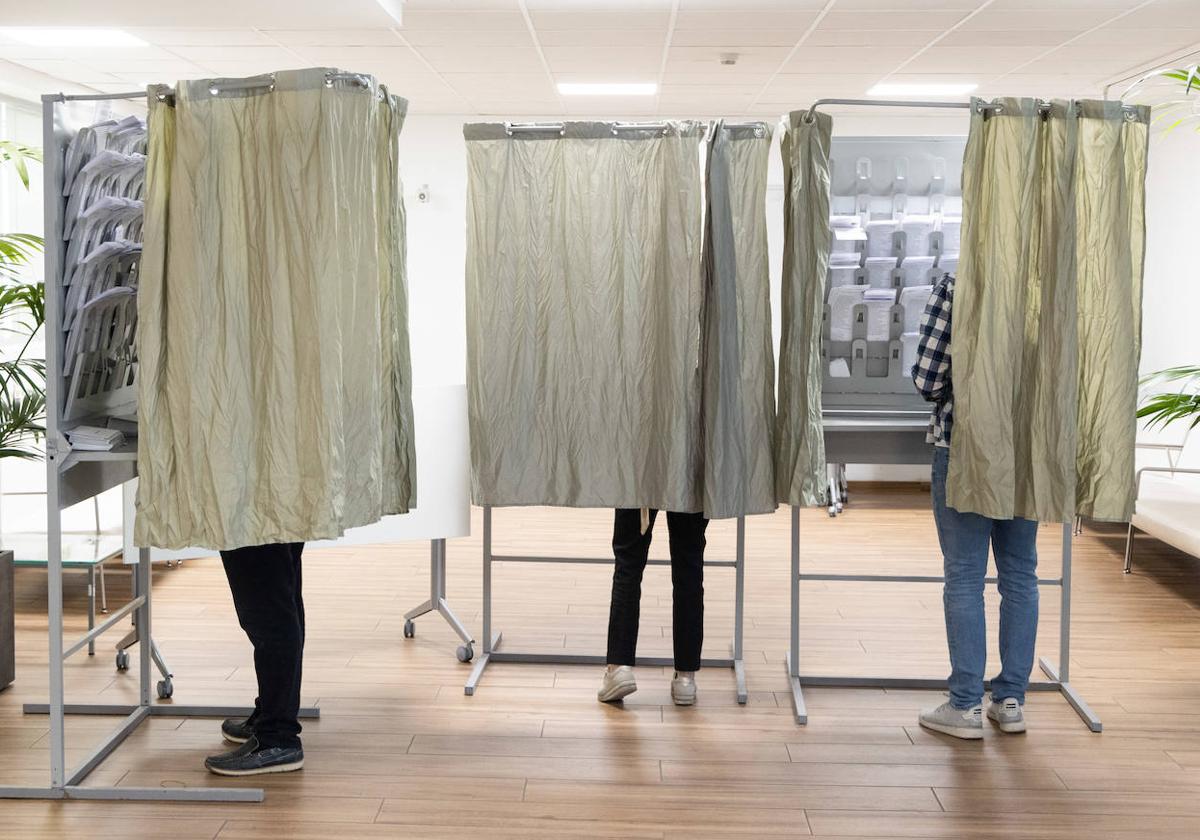 Tres electores eligen papeleta el 28-M en un colegio electoral de Valladolid.