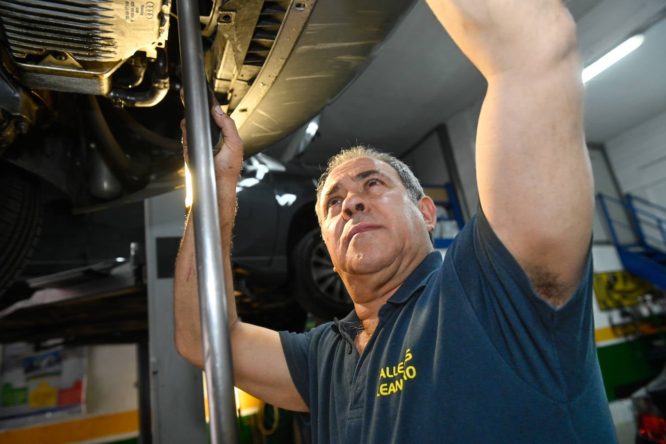 Leandro arreglando un vehículo en su taller mecánico.