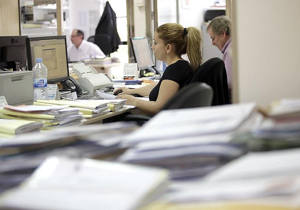 Funcionarios rodeados de expedientes pendientes de tramitación.