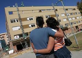 Una pareja de jóvenes observa la construcción de unas viviendas.