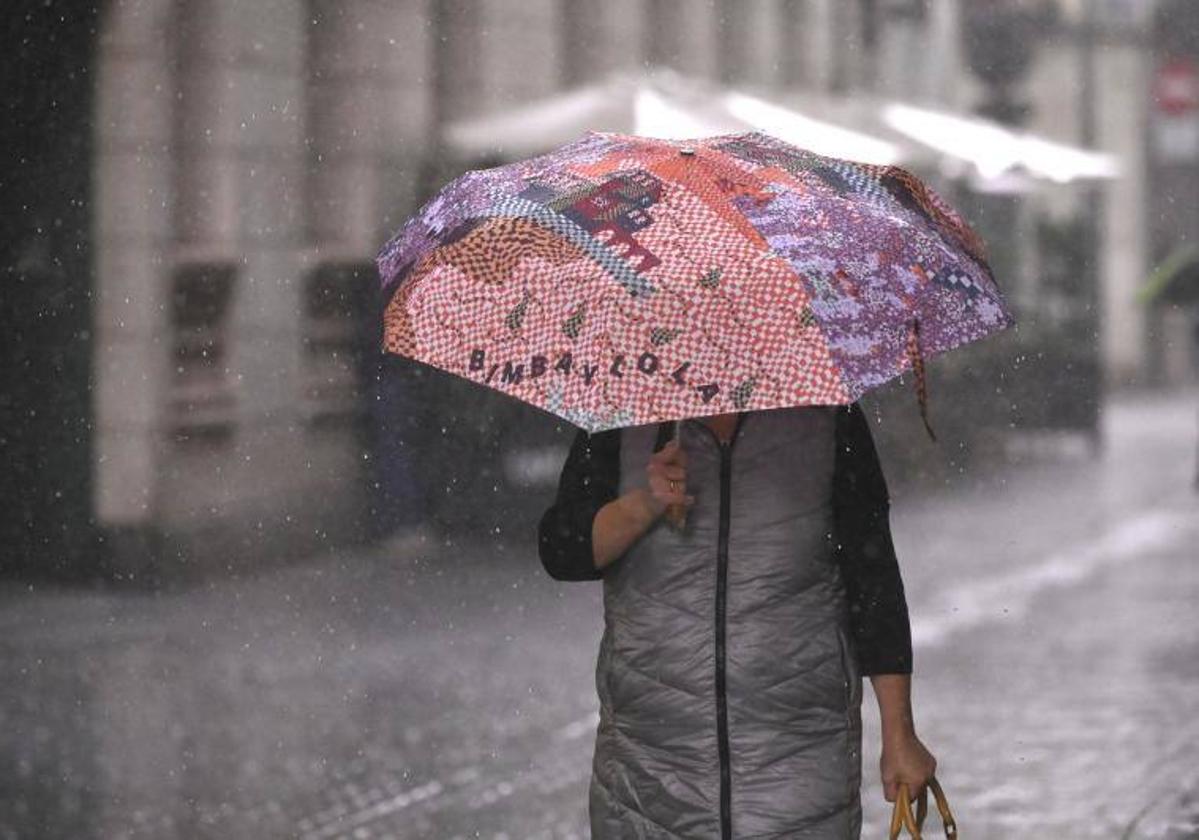 Una mujer se protege de la lluvia en Valladolid.