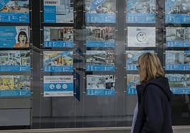 Una mujer observa el escaparate de una inmobiliaria.