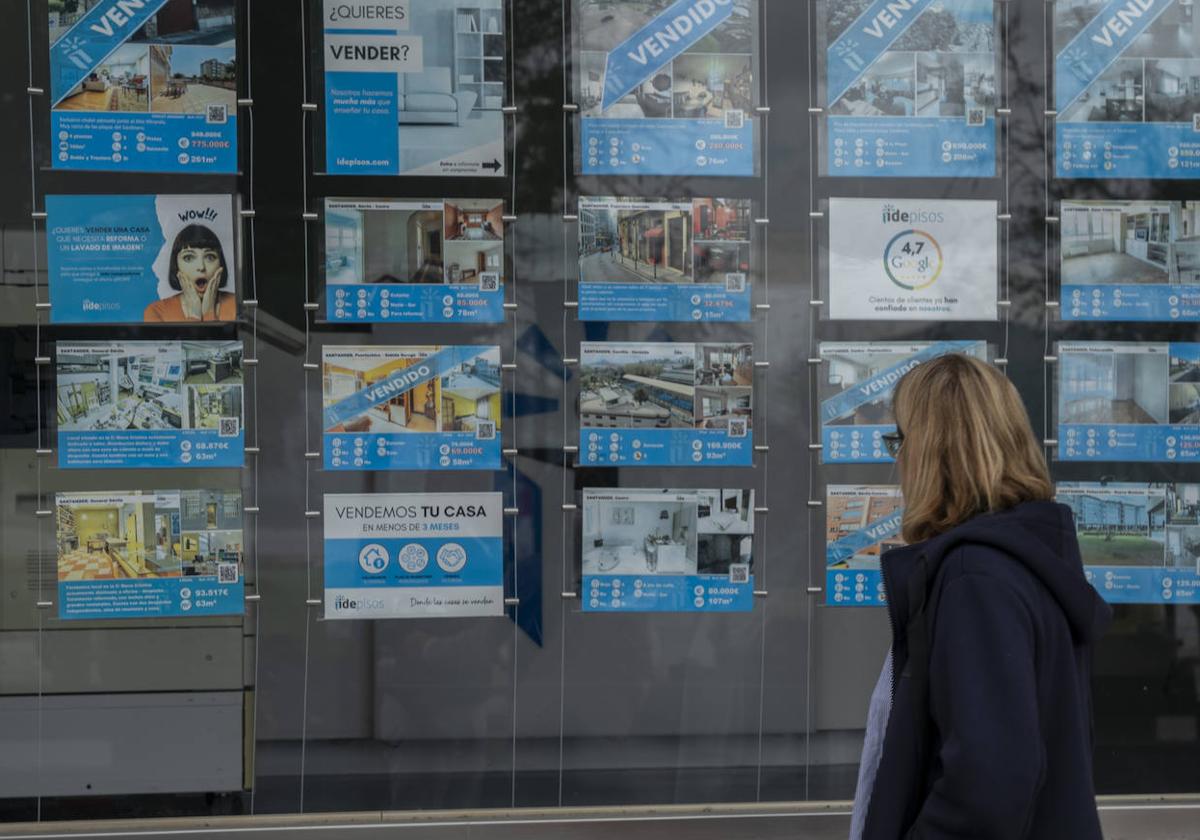 Una mujer observa el escaparate de una inmobiliaria.