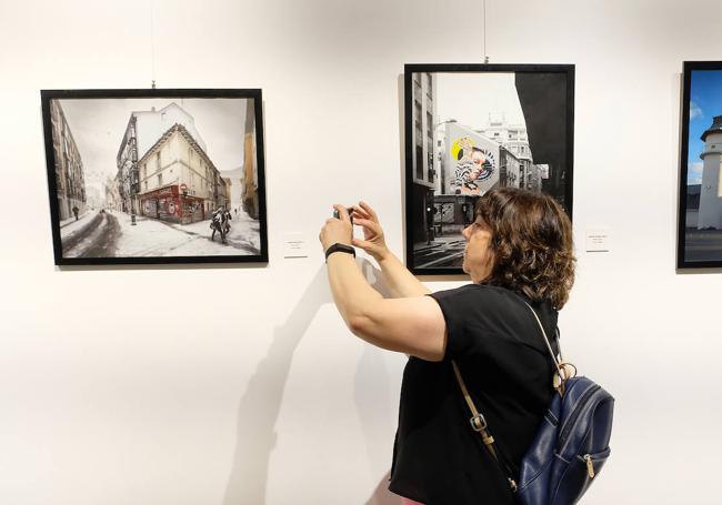 Una visitante toma imágenes de las fotografías de la muestra.