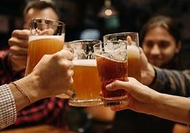 Varias personas brindan con diferentes cervezas.
