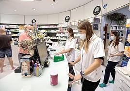 El personal de una farmacia de Valladolid, con mascarilla en su puesto de trabajo.