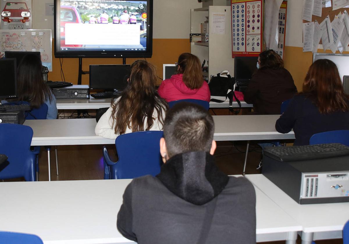 Varios alumnos atienden las explicaciones de su profesor de autoescuela.