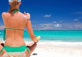 Una mujer se aplica crema solar en la playa.