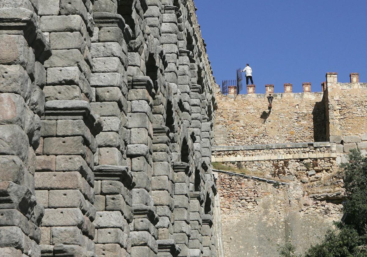 Un hombre, subido a la muralla junto al Acueducto en la zona del Postigo.