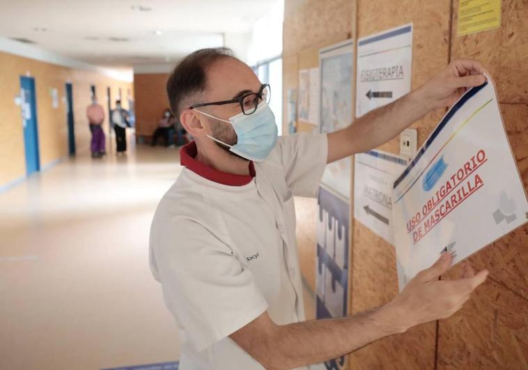 Enfermero quitando cartel de uso obligatorio de mascarillas.