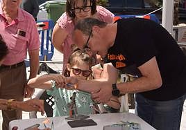 Un artesano del vidrio enseña a una niña a usar un soplete.