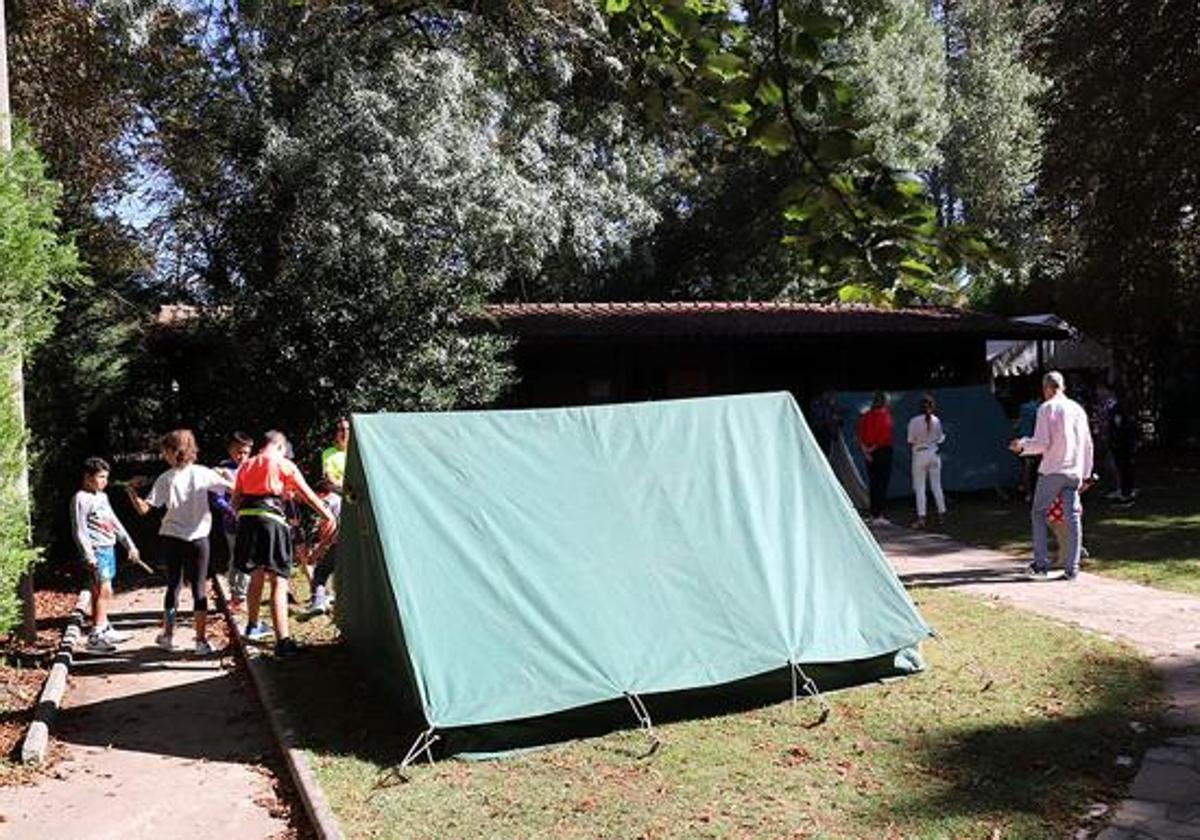 Varios niños cerca de una tienda de campaña en un campamento de verano.