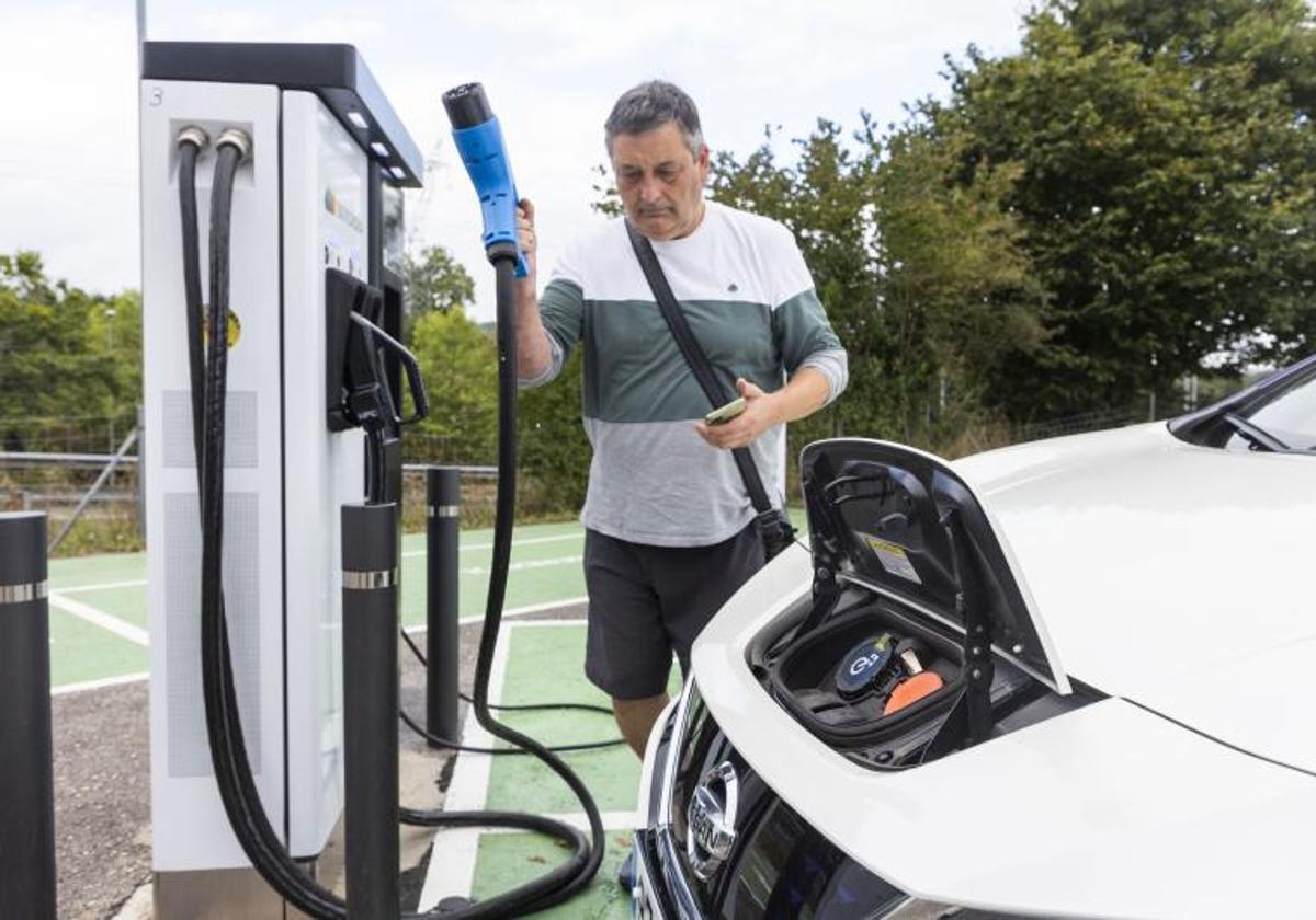 Un hombre carga su coche en un poste eléctrico.