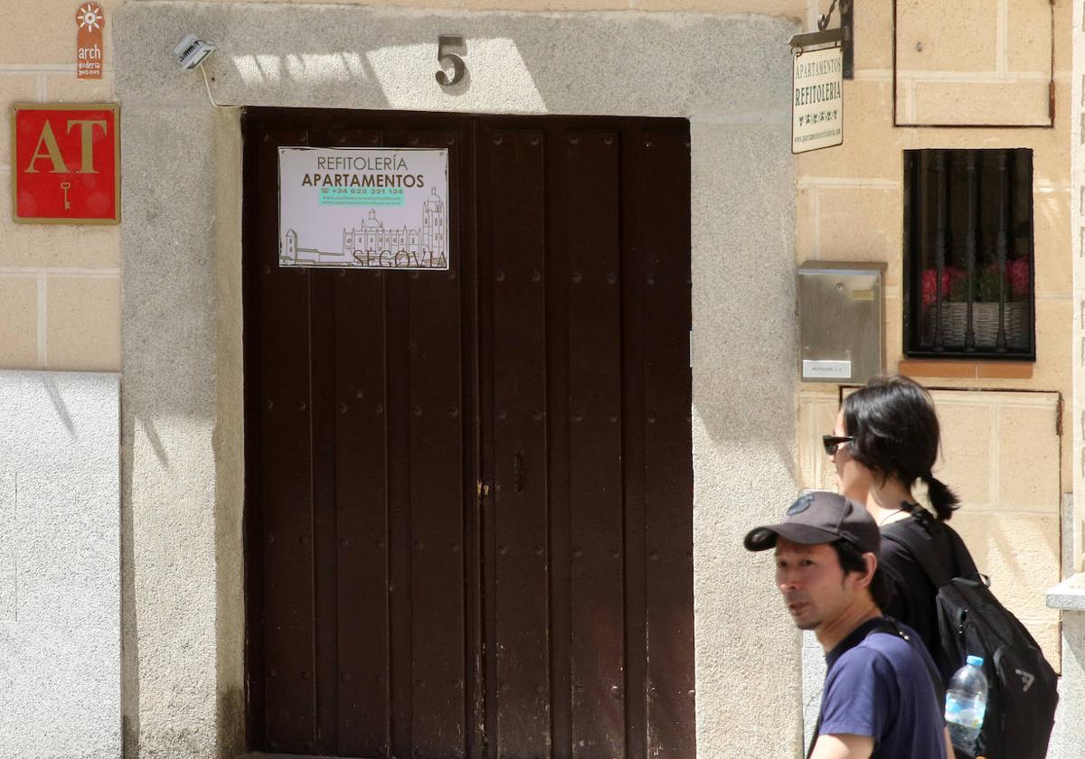 Dos turistas asiáticos pasan por delante de un inmueble de apartamentos turísticos acreditado, como señala la placa de la puerta.