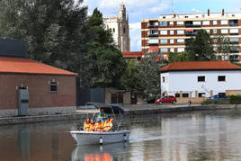 Un abuelo y sus nietos disfrutan de un paseo en barco por la dársena del Canal de Castilla.
