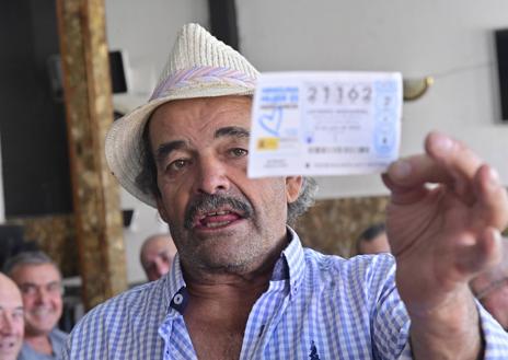 Imagen secundaria 1 - El segundo premio de la Lotería no interrumpe la partida de mus en Ataquines. Javier Sanz muestra su décimo y detalle del 21.162 en las manos de Florentino Fernández.