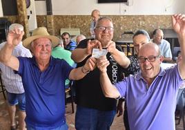 Algunos de los agraciados celebran en el bar Mario de Ataquines que les ha tocado la Lotería con uno de los décimos premiados en la mano.