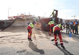 Los bomberos ayudan a retirar la carga del camión volcado.
