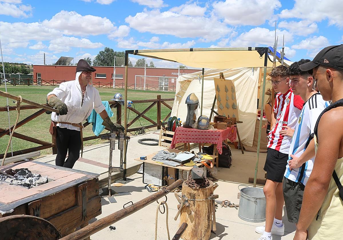 Unos jóvenes observan el trabajo de la forja en el mercado de Hornillos de Cerrato.