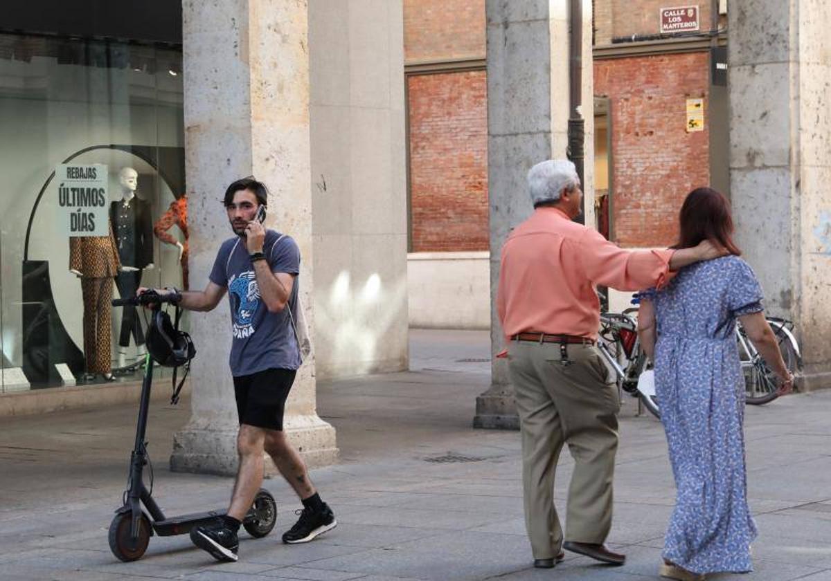 Imagen de archivo de una pareja agarrada y un hombre en patinete eléctrico en la Calle Mayor de Palencia.