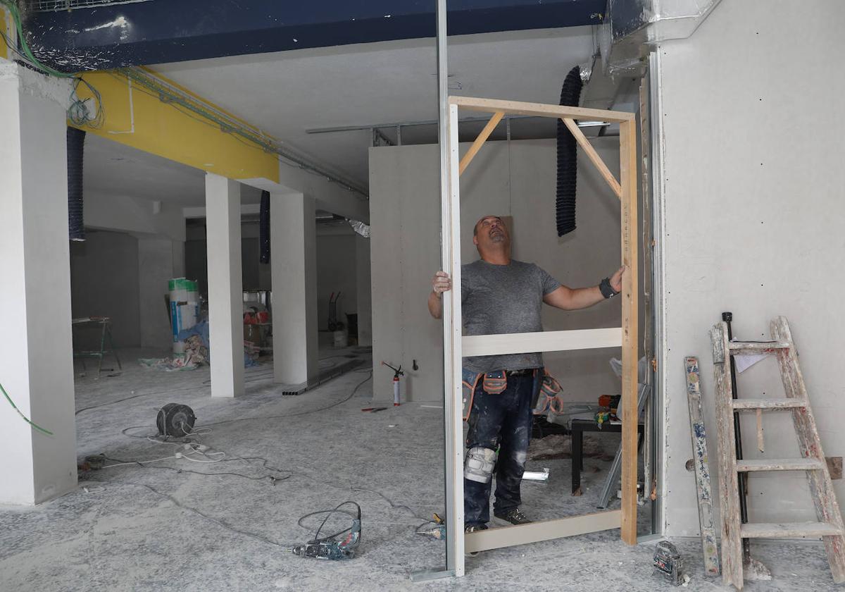 Un trabajador mide un marco para continuar con el tabicado del local.