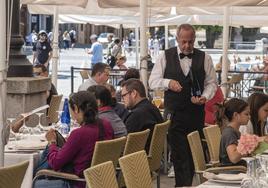 Un trabajador hostelero atiende a los clientes de una terraza en Segovia.