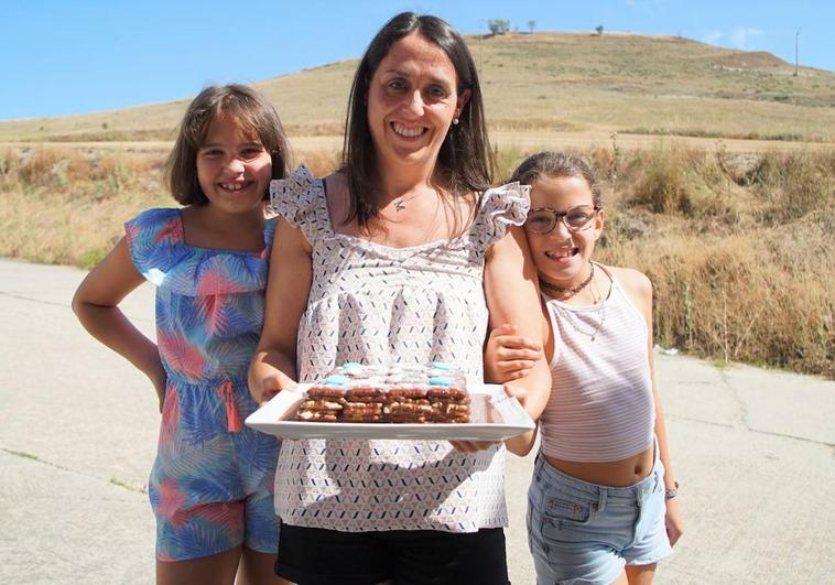 Mónica con sus hijas Estefanía y Claudia y su tarta de galletas y al fondo, El Cueto de Castrodeza.