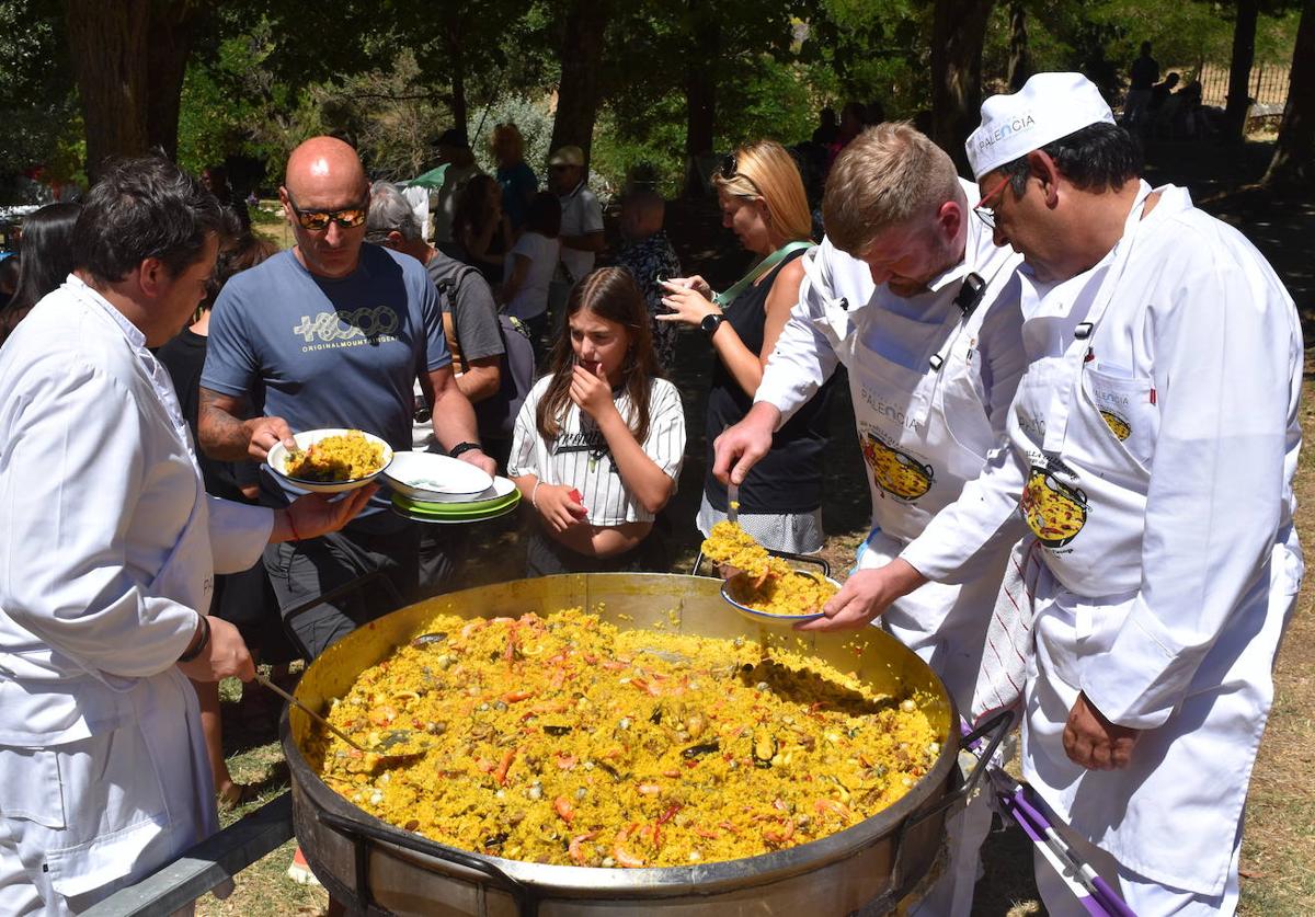 Los cocineros sirven este domingo raciones de paella a los asistentes a la fiesta.