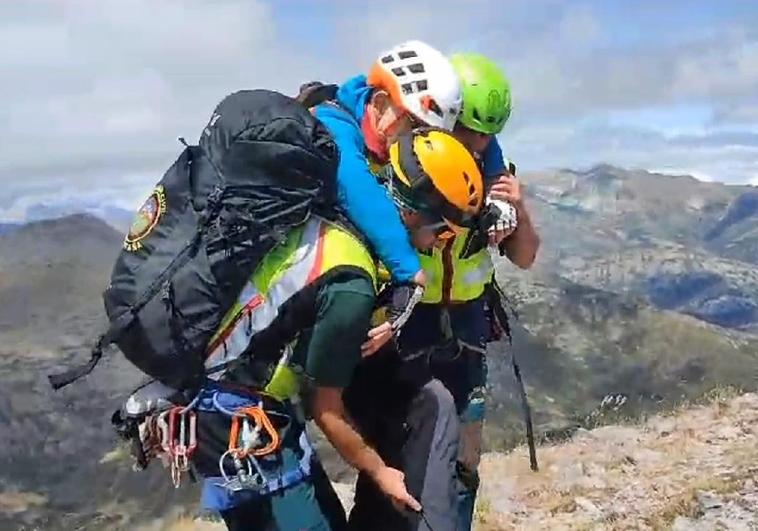 Dos agentes del Grupo de Rescate Especial de Intervención en Montaña llevan al montañero al punto de extracción.