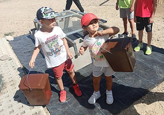 Dos niños acuden con sus residuos orgánicos a la planta de compost de Castrodeza
