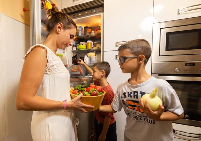 Sara y sus hijos guardando la compra y las verduras de la huerta en el frigorífico