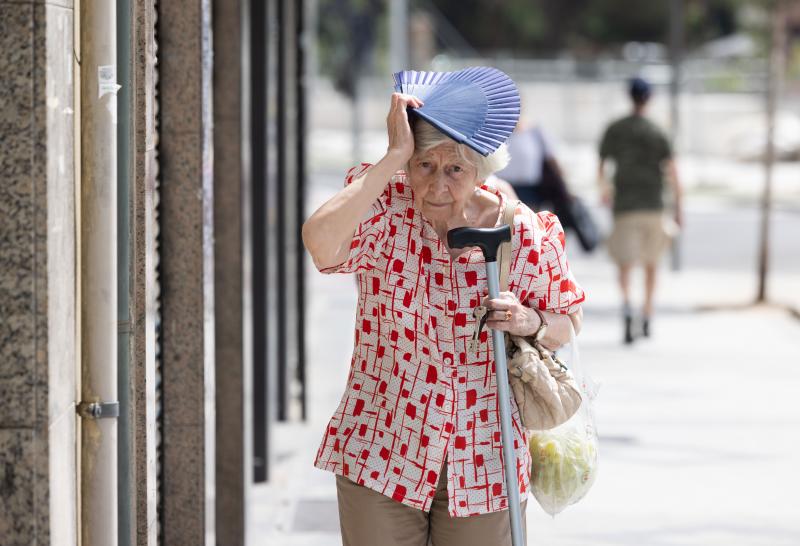 Una mujer se resguarda del calor con su abanico.